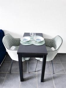 a black table with two chairs and two wine glasses at STUDIO COSY PROCHE PLAGE, tout à pied in Pornichet +38 photos