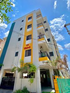 a white and yellow building with trees in front of it at Joy Suites and Hostel in Pune