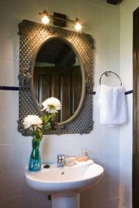 baño con lavabo con espejo y jarrón con flores en Apartamentos Santillana del Mar en Santillana del Mar