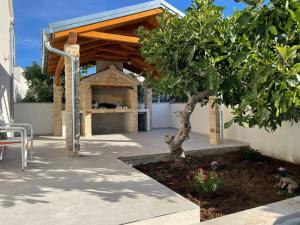 a patio with a stone fireplace with a wooden roof at Your private summer house in Vodice