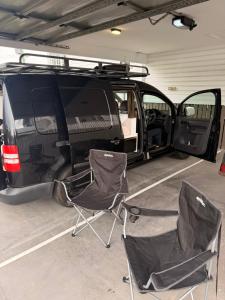 a van parked in a garage with two chairs at Caddy Car in Brisbane