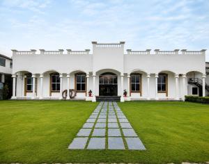 a large white house with a green yard at Kamaksha Palace in Sundarnagar