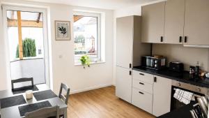 a kitchen with white cabinets and a table and a dining room at Apartment -Wohnung Herford in Herford
