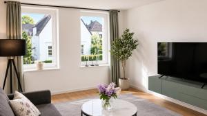 a living room with a couch and a tv and windows at Apartment -Wohnung Herford in Herford