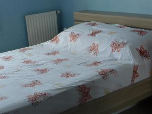 a bed with white sheets with red flowers on it at Chambre chez l'habitant Nice Baie des Anges in Nice