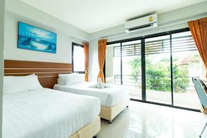 a bedroom with two beds and a large window at Prosperous in Hat Yai