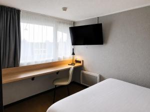 a room with a desk with a bed and a window at Kyriad Direct Le Bourget Gonesse in Gonesse +14 photos