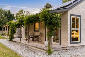 a house with a porch with a table and ivy at Arrow Junction Cottage in Arrowtown