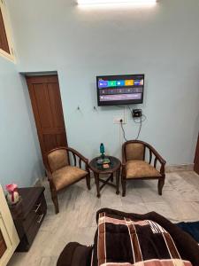 a living room with two chairs and a tv on the wall at RAMRAJ GUEST House in Ayodhya +13 photos