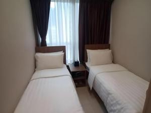 two twin beds in a hotel room with a window at WE Hotel Kowloon in Hong Kong