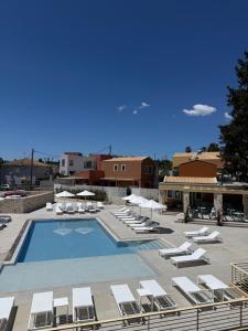 a large swimming pool with lounge chairs and umbrellas at Tessera Boutique Hotel & Villas Collection in Gouvia
