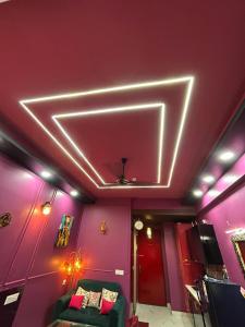 a living room with pink walls and a green couch at THE MOONLIGHT STUDIo in Ghaziabad