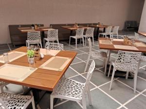 a restaurant with wooden tables and white chairs at Shubham Resort in Bhilwara