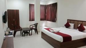 a bedroom with a bed and a desk and chairs at Shubham Resort in Bhilwara +1 photo