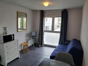 a living room with a blue couch and a window at STUDIO COSY PROCHE PLAGE, tout à pied in Pornichet