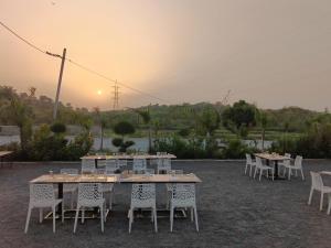 a group of tables and chairs with the sunset in the background at Shubham Resort in Bhilwara