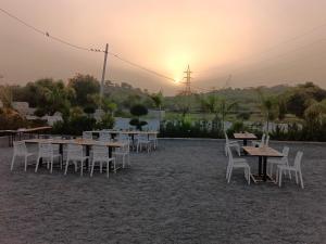 a group of tables and chairs with the sunset in the background at Shubham Resort in Bhilwara