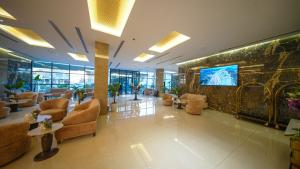 a lobby with couches and a tv in a building at BAZ Hotel Airport Road in Baghdād