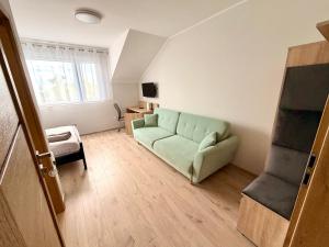 a living room with a green couch and a chair at Willa Dominik 2 in Jastarnia