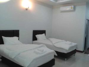 two beds in a room with white sheets at N-Joy Place in Surin