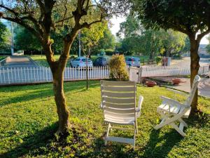 two white chairs sitting next to a tree at Al Melograno - Villetta - Gussago - Franciacorta in Gussago