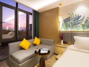 a bedroom with a bed and a couch and a chair at mango crystal hotel in Haikou