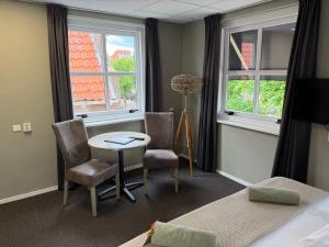 a room with a table and chairs and two windows at Hotel Willemstad - kleinschalig hotel in Willemstad