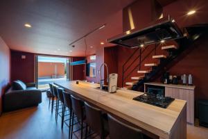 a kitchen with a bar with chairs and a staircase at THE SECOND Chousei Beach Village in Jōnouchi