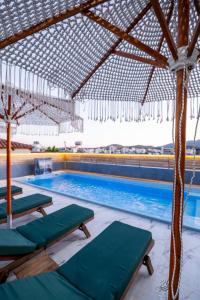a swimming pool with chaise lounge chairs and an umbrella at Vila Naço Ksamil in Ksamil