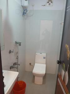 a white bathroom with a toilet and a sink at Dolphin beach in Varkala
