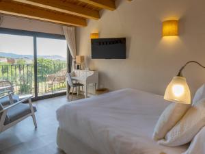 a bedroom with a bed and a desk and a window at Hotel Boutique Niu de Sol - Designed for Adults in Palau-Saverdera