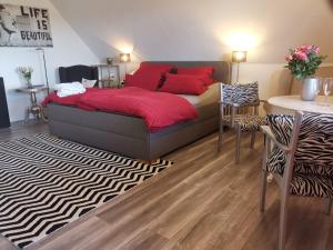 a bedroom with a bed with red pillows and a table at Appartement am Kirnbergsee in Bräunlingen