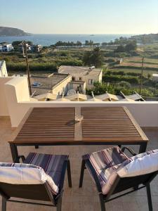 a wooden table and two chairs on a balcony at Leros 'Sundown' Guest house in Gourna