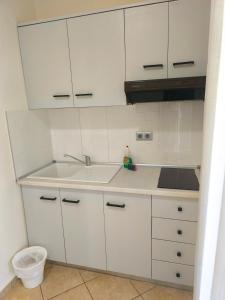a kitchen with white cabinets and a sink at Kiparissis Apartments in Kriopigi +81 photos