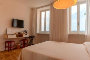 a bedroom with a bed and two windows and a tv at Ai Pesci Room Rental in Riomaggiore