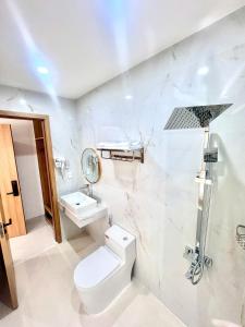 a white bathroom with a toilet and a sink at Khách Sạn Anh Khoa 2 in Phan Rang–Tháp Chàm
