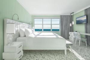a bedroom with a large white bed and a desk at COMO Metropolitan Miami Beach in Miami Beach