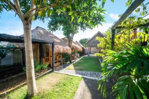 a row of houses with thatched roofs and a yard at Bali Bio Villas in Uluwatu