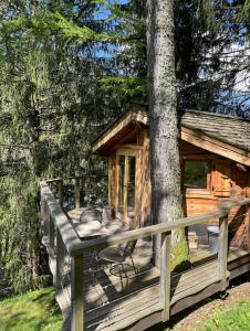 a wooden deck with a cabin with a tree at Entre les Arbres in Saint-Jean-d'Aulps