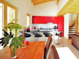 cocina con mesa de madera y armarios rojos en Charming Private Bungalow in Wohlenberg on Natural Beach, en Hérémence