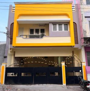 a yellow building with a black fence in front of it at Villa Yogalakshmi in Chidambaram