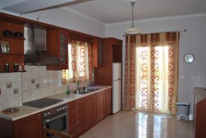 a kitchen with wooden cabinets and a sink and a refrigerator at Βίλλα Αντρέας in Karavomylos
