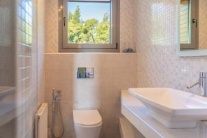 a bathroom with a sink and a toilet and a window at The Quite Blue villa in Kriopigi +52 photos