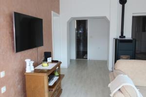 a living room with a couch and a tv on a wall at Holiday House Vego in Čapljina