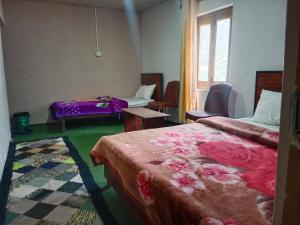 a room with two beds and a table and a window at Mullberry Lodge Gulmit in Chamangul