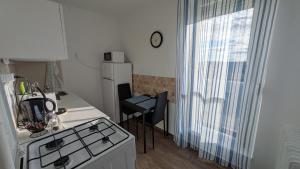 a kitchen with a stove and a table and a window at Magaslak Apartman in Kaposvár