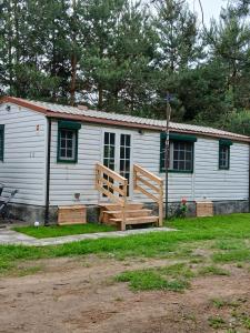 a white cabin with a large porch and a wooden deck at Sosnowa Polana in Lipinki