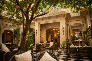 an outdoor patio with chairs and a tree at Kaner Bagh A Heritage Boutique Hotel in Udaipur