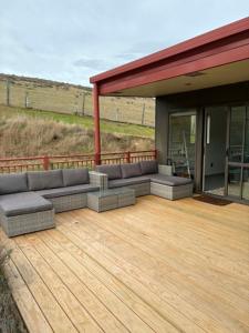 a patio with couches sitting on a wooden deck at Clydesvale Apartment in Clyde