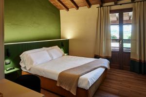 a bedroom with a bed with a green wall and a window at AGRITURISMO RIPA DEL BOSCO in Capriolo
